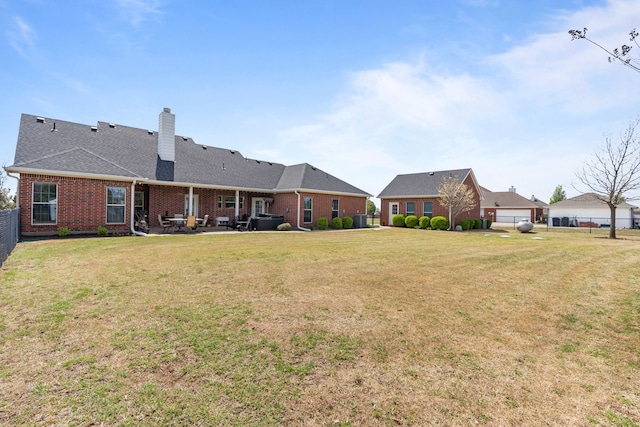 rear view of property with fence, a patio, a chimney, brick siding, and a yard