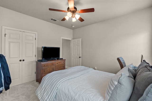 bedroom with a closet, visible vents, a ceiling fan, and light carpet