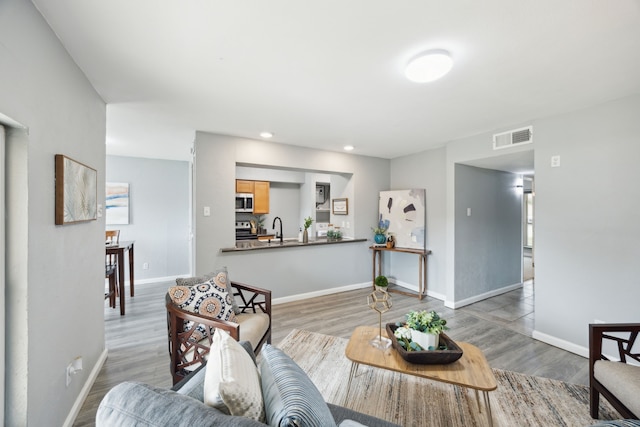 living room with wood finished floors, baseboards, and visible vents