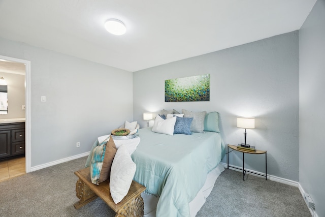 bedroom with ensuite bathroom, light colored carpet, and baseboards