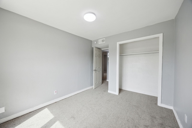 unfurnished bedroom featuring carpet flooring, a closet, baseboards, and visible vents