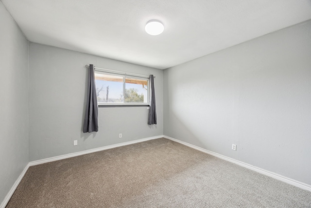 carpeted spare room featuring baseboards