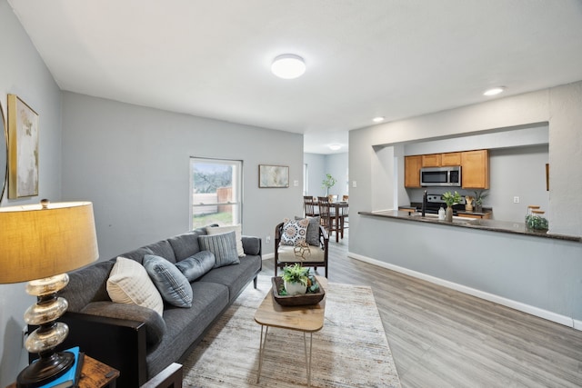 living area with baseboards, wood finished floors, and recessed lighting