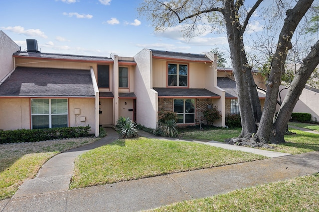 view of front facade featuring a front lawn, stucco siding, and brick siding