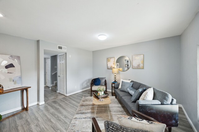 living room featuring baseboards, visible vents, and wood finished floors