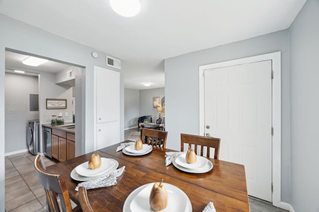 dining area featuring light tile patterned flooring, baseboards, separate washer and dryer, and visible vents