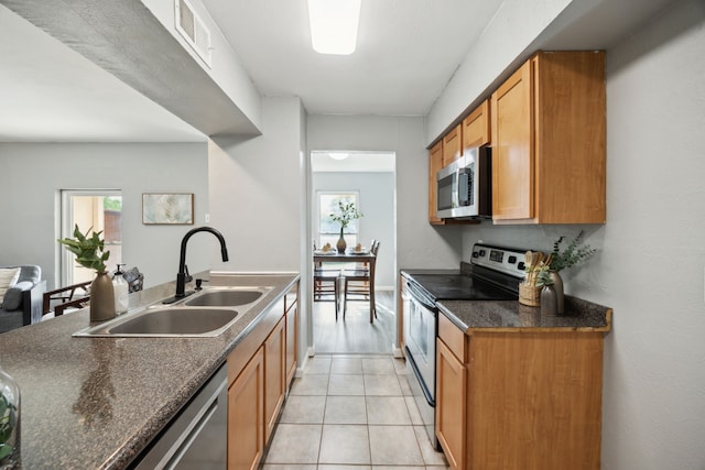 kitchen featuring light tile patterned floors, a sink, dark countertops, visible vents, and appliances with stainless steel finishes