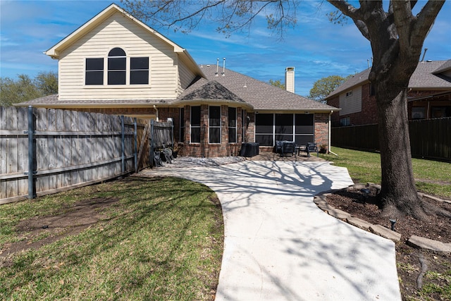 1808 Paddington Ct, Arlington, TX 76017 - back of house featuring brick siding, a sunroom, a patio area, a chimney, and driveway