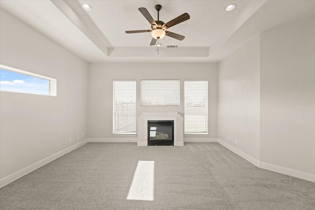 153 Whispering Winds Dr, Gunter, TX 75058 - unfurnished living room featuring a raised ceiling, a glass covered fireplace, recessed lighting, ceiling fan, and carpet flooring