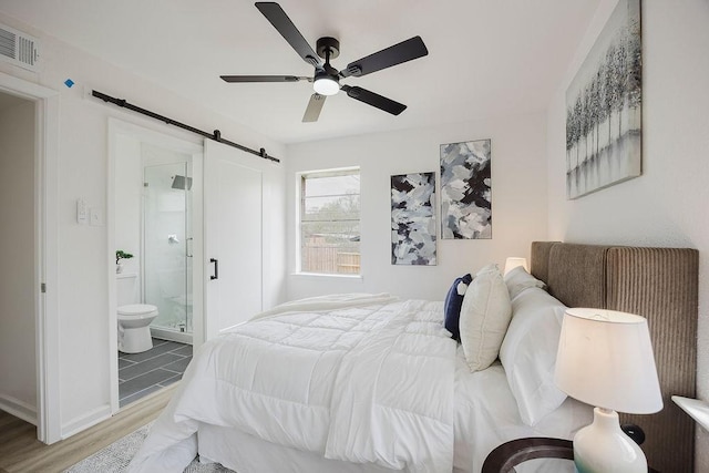 2112 Pontiac Dr, Carrollton, TX 75006 - bedroom with a barn door, visible vents, a ceiling fan, ensuite bathroom, and wood finished floors