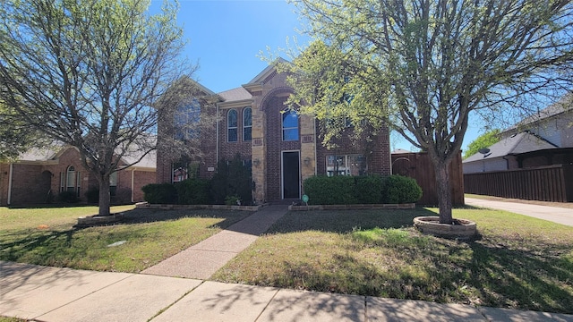 traditional-style home with brick siding, a front yard, and fence