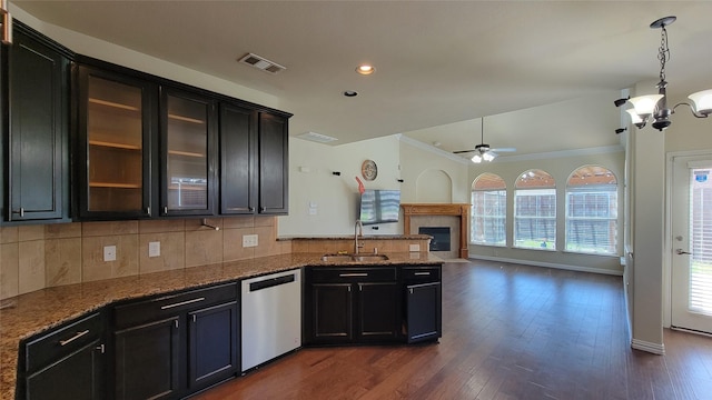 kitchen featuring tasteful backsplash, ceiling fan with notable chandelier, stainless steel dishwasher, a sink, and a tiled fireplace