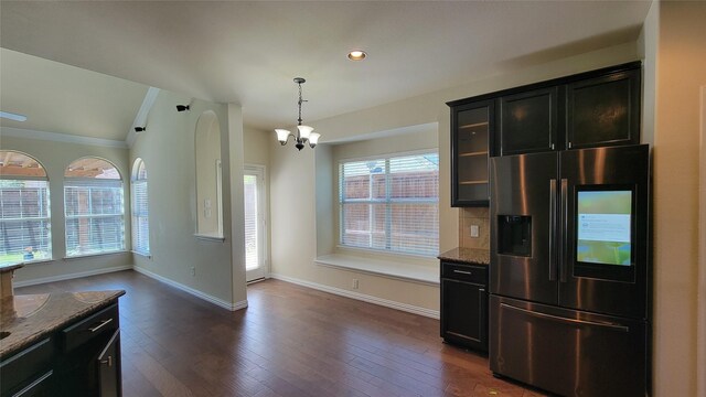 kitchen featuring glass insert cabinets, dark stone counters, refrigerator with ice dispenser, and a chandelier