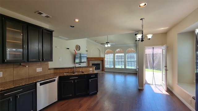 kitchen with visible vents, a peninsula, stainless steel dishwasher, a sink, and backsplash