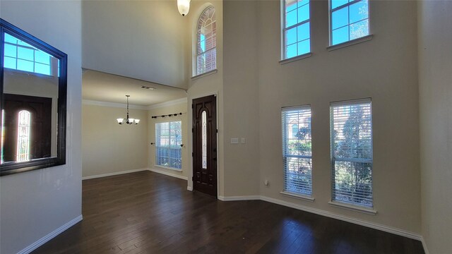 foyer entrance with ornamental molding, baseboards, a chandelier, dark wood finished floors, and a high ceiling