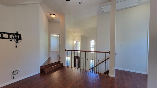 hall featuring an upstairs landing, attic access, wood-type flooring, baseboards, and visible vents