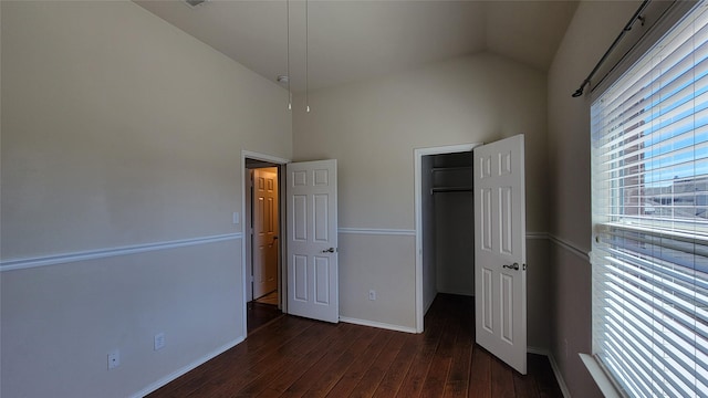 unfurnished bedroom with hardwood / wood-style floors, a closet, vaulted ceiling, and a spacious closet