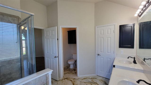bathroom with marble finish floor, toilet, lofted ceiling, a sink, and a stall shower