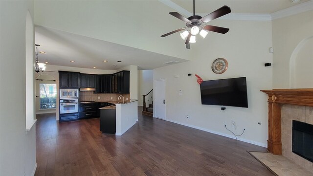 kitchen featuring open floor plan, backsplash, a sink, dark wood-style floors, and appliances with stainless steel finishes