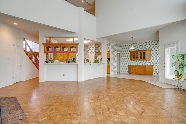 1002 Loch Lomond Dr, Arlington, TX 76012 - unfurnished living room featuring a high ceiling, wallpapered walls, plenty of natural light, and baseboards