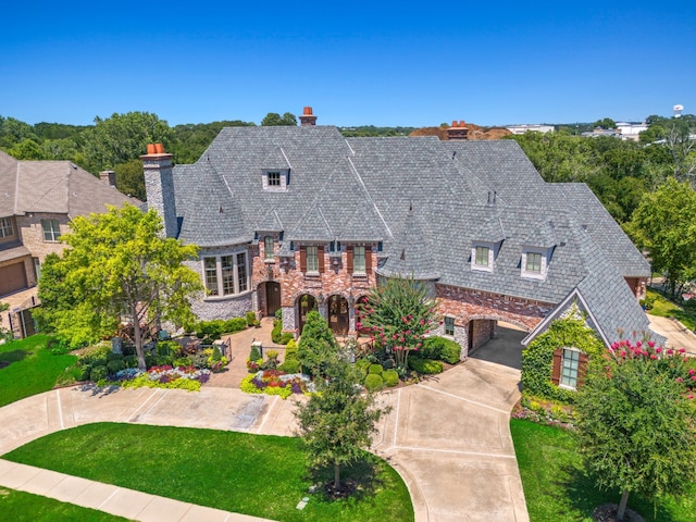 view of front of house featuring a high end roof, a chimney, a front lawn, and stone siding