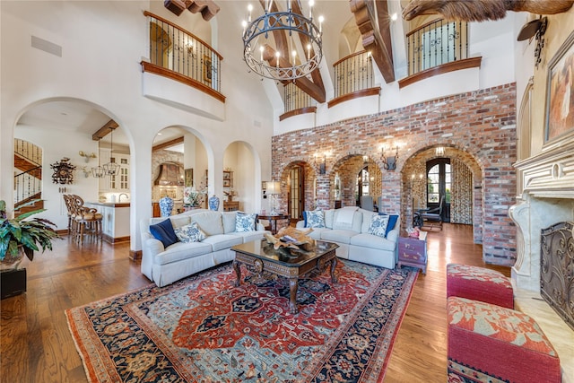 living area featuring a high ceiling, wood finished floors, visible vents, arched walkways, and a chandelier