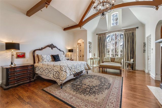 bedroom featuring arched walkways, baseboards, a notable chandelier, wood finished floors, and high vaulted ceiling