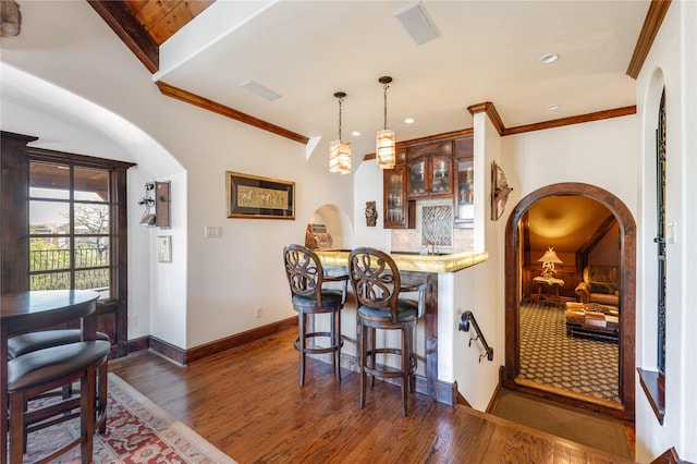 bar featuring arched walkways, wet bar, dark wood finished floors, baseboards, and ornamental molding
