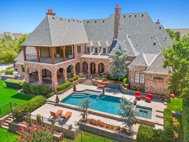 rear view of property with brick siding, a patio area, a chimney, and a fenced backyard