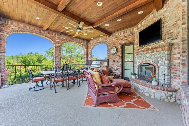 view of patio featuring outdoor dining area, a fireplace, an outdoor kitchen, a ceiling fan, and a grill