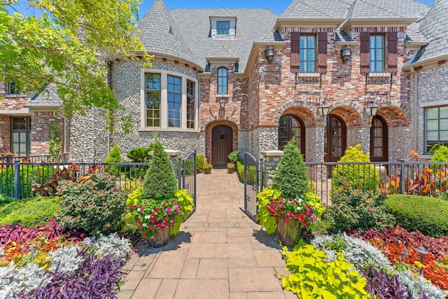 view of front of home with a high end roof, a gate, brick siding, and a fenced front yard