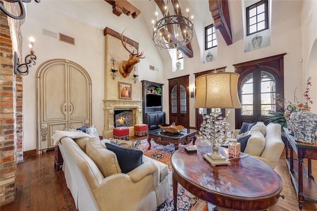 living area with hardwood / wood-style flooring, baseboards, a fireplace, a notable chandelier, and a high ceiling