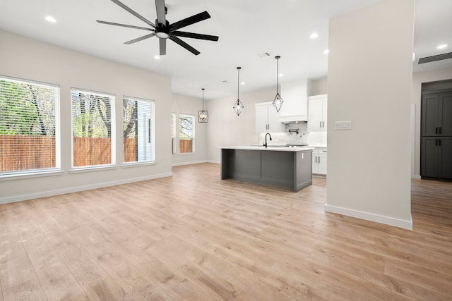 unfurnished living room with a ceiling fan, light wood-style floors, and visible vents
