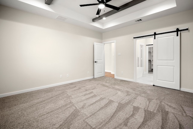 unfurnished bedroom featuring baseboards, visible vents, carpet, and a raised ceiling