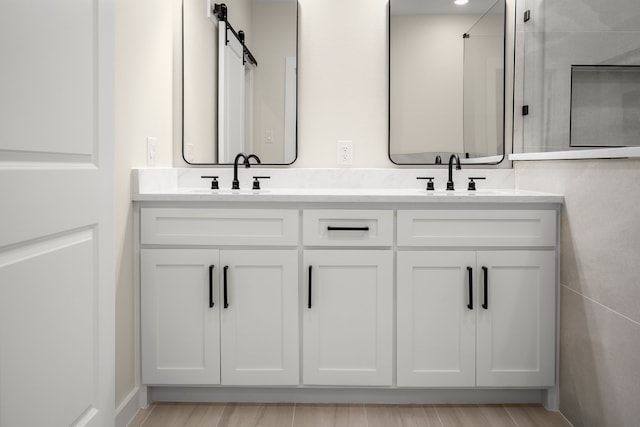 full bathroom featuring double vanity, wood finished floors, and a sink