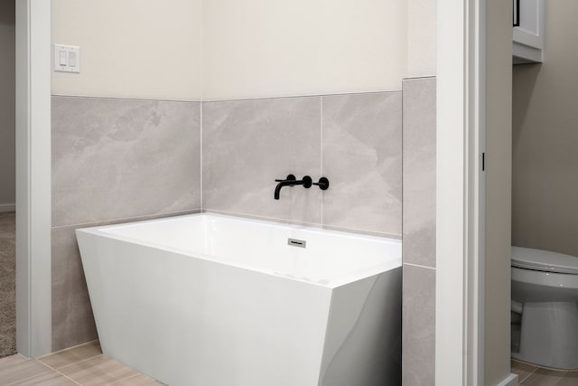 full bathroom with a soaking tub, toilet, and tile walls