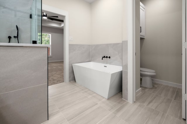 full bath with toilet, tile patterned floors, tile walls, and a freestanding bath