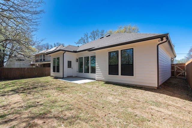 rear view of house featuring a fenced backyard, a shingled roof, a patio area, and a yard