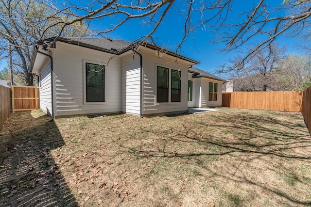 rear view of property with a lawn and a fenced backyard