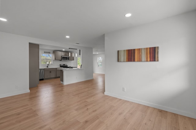 2225 Mack Ln, Dallas, TX 75227 - unfurnished living room with recessed lighting, light wood-style flooring, baseboards, and a sink