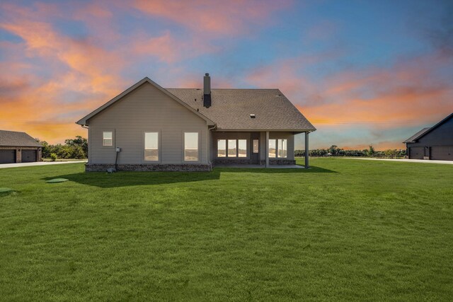 4133 Old Springtown Rd, Weatherford, TX 76085 - back of property at dusk with a lawn, a chimney, a detached garage, and a patio area