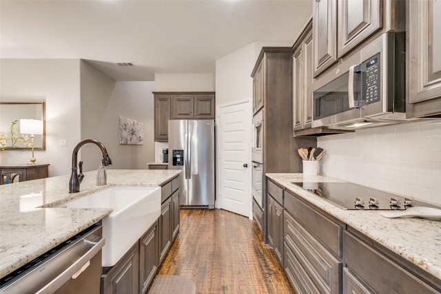 kitchen with dark wood-style floors, backsplash, a sink, dark brown cabinetry, and appliances with stainless steel finishes