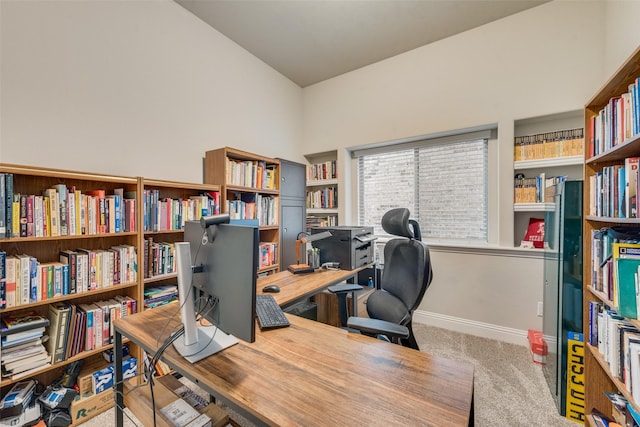 carpeted office featuring lofted ceiling and baseboards