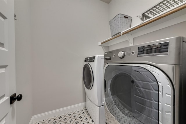 laundry area with light floors, baseboards, washer and clothes dryer, and laundry area