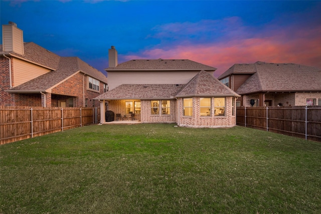 back of property at dusk featuring a patio area, a fenced backyard, and brick siding