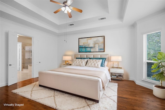 bedroom featuring wood finished floors, a tray ceiling, crown molding, and visible vents