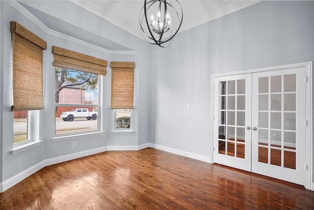 spare room featuring french doors, baseboards, ornamental molding, wood finished floors, and an inviting chandelier