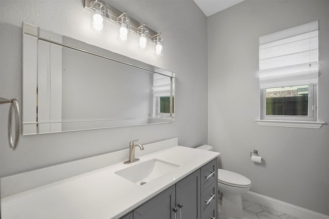 bathroom featuring marble finish floor, vanity, toilet, and baseboards