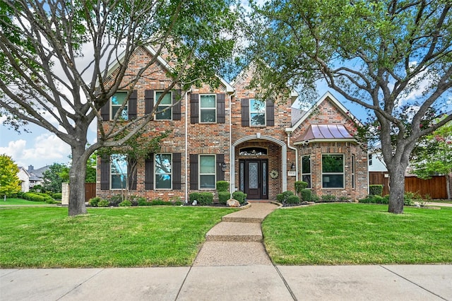 view of front of home with brick siding, fence, and a front lawn