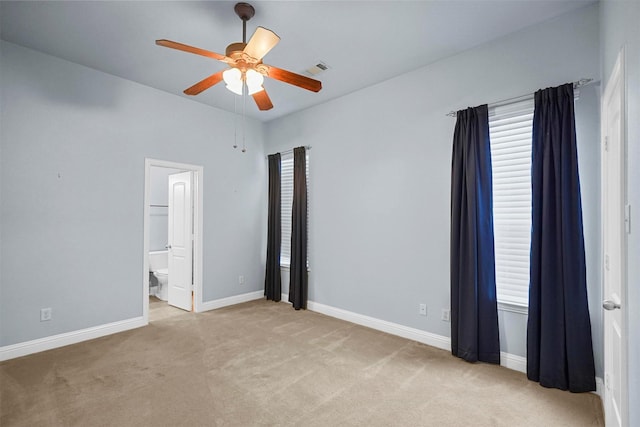unfurnished bedroom featuring a ceiling fan, light carpet, ensuite bathroom, baseboards, and visible vents
